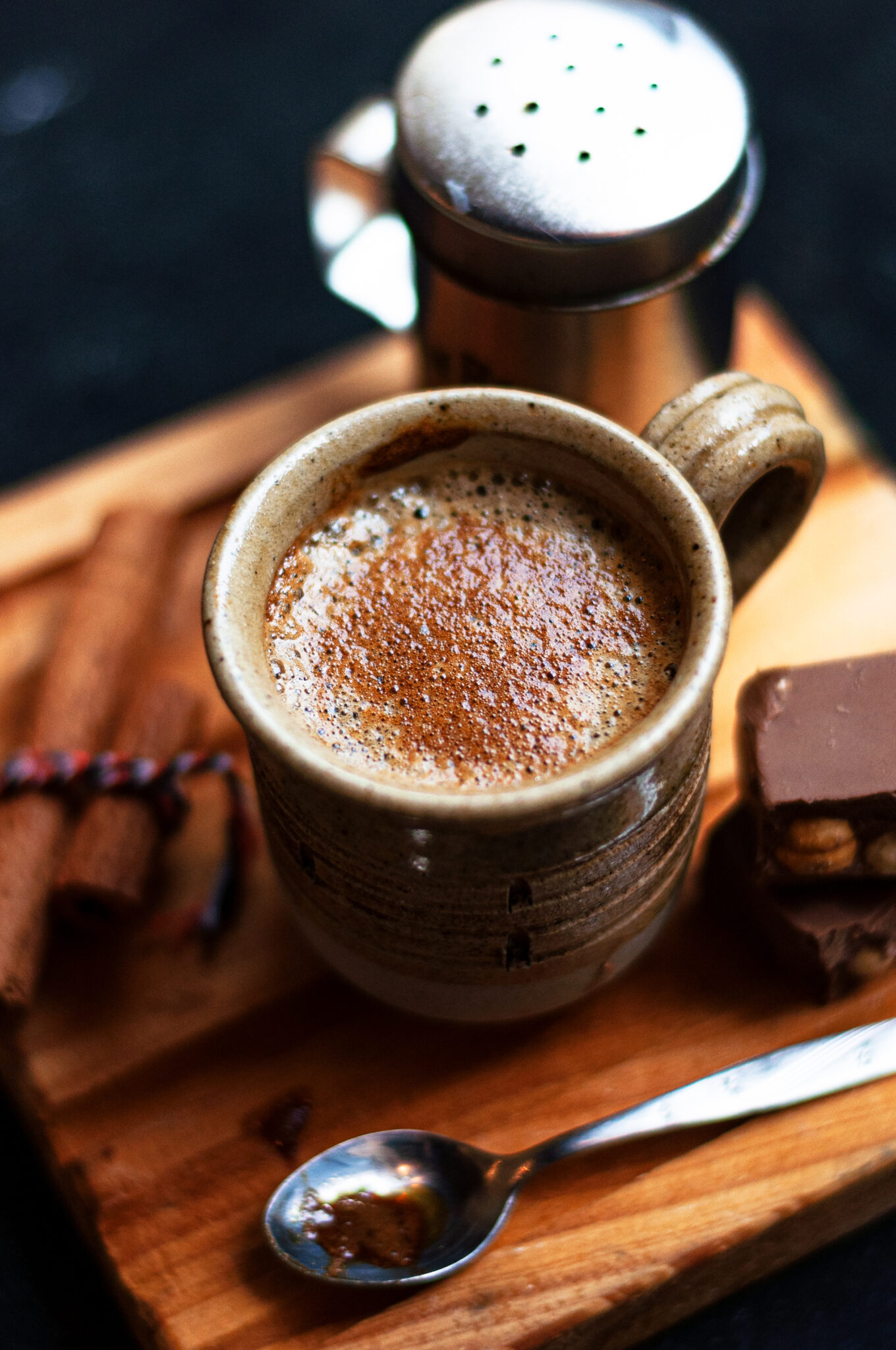 cup of coffee with cinnamon sticks and chocolate cookies on a wooden board